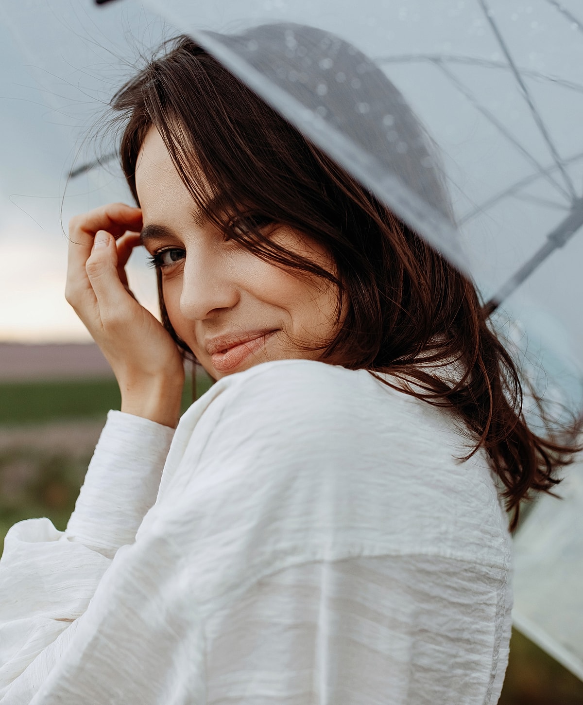 Woman smiling under a rain umbrella.