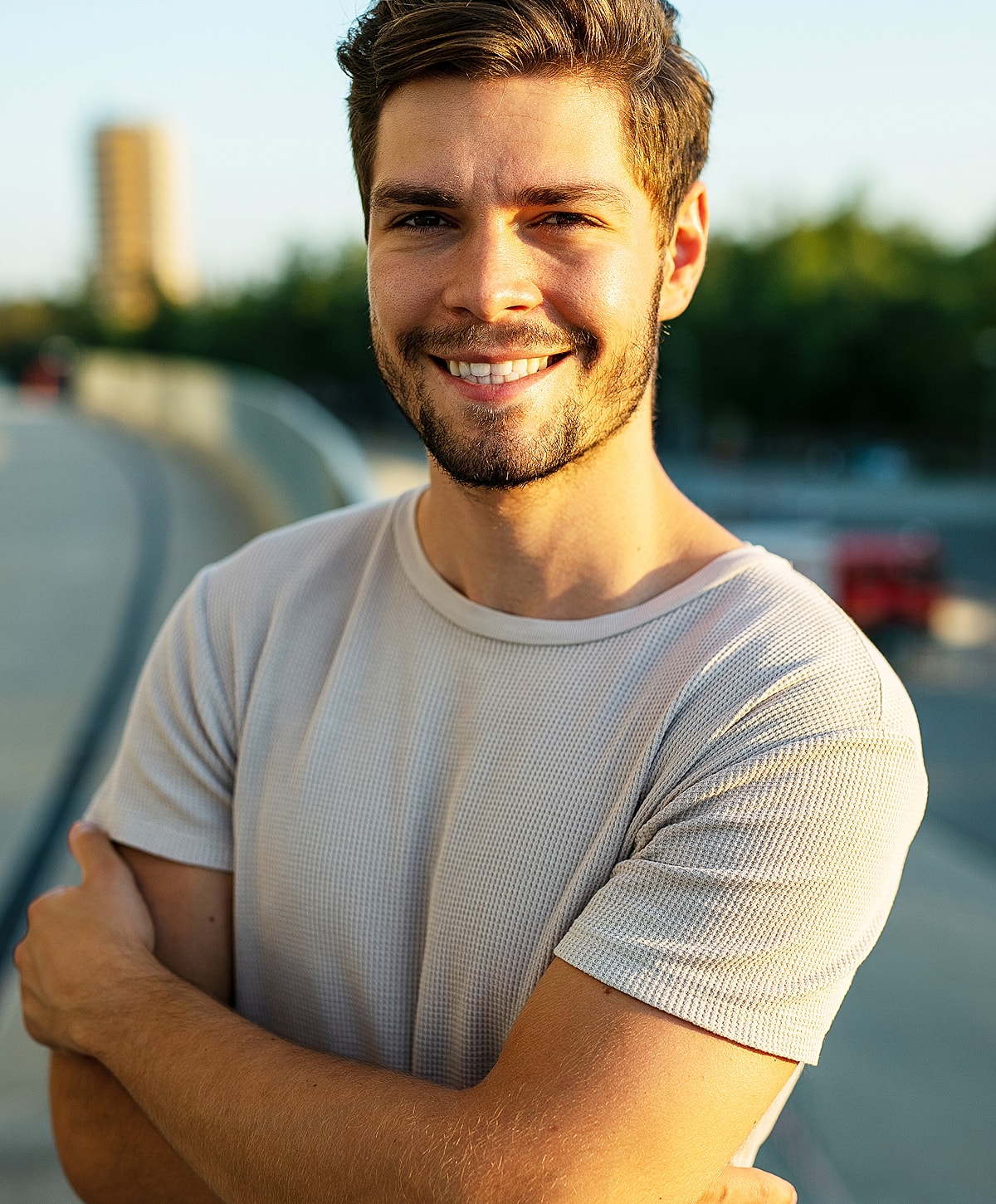 Smiling man with arms crossed outdoors.