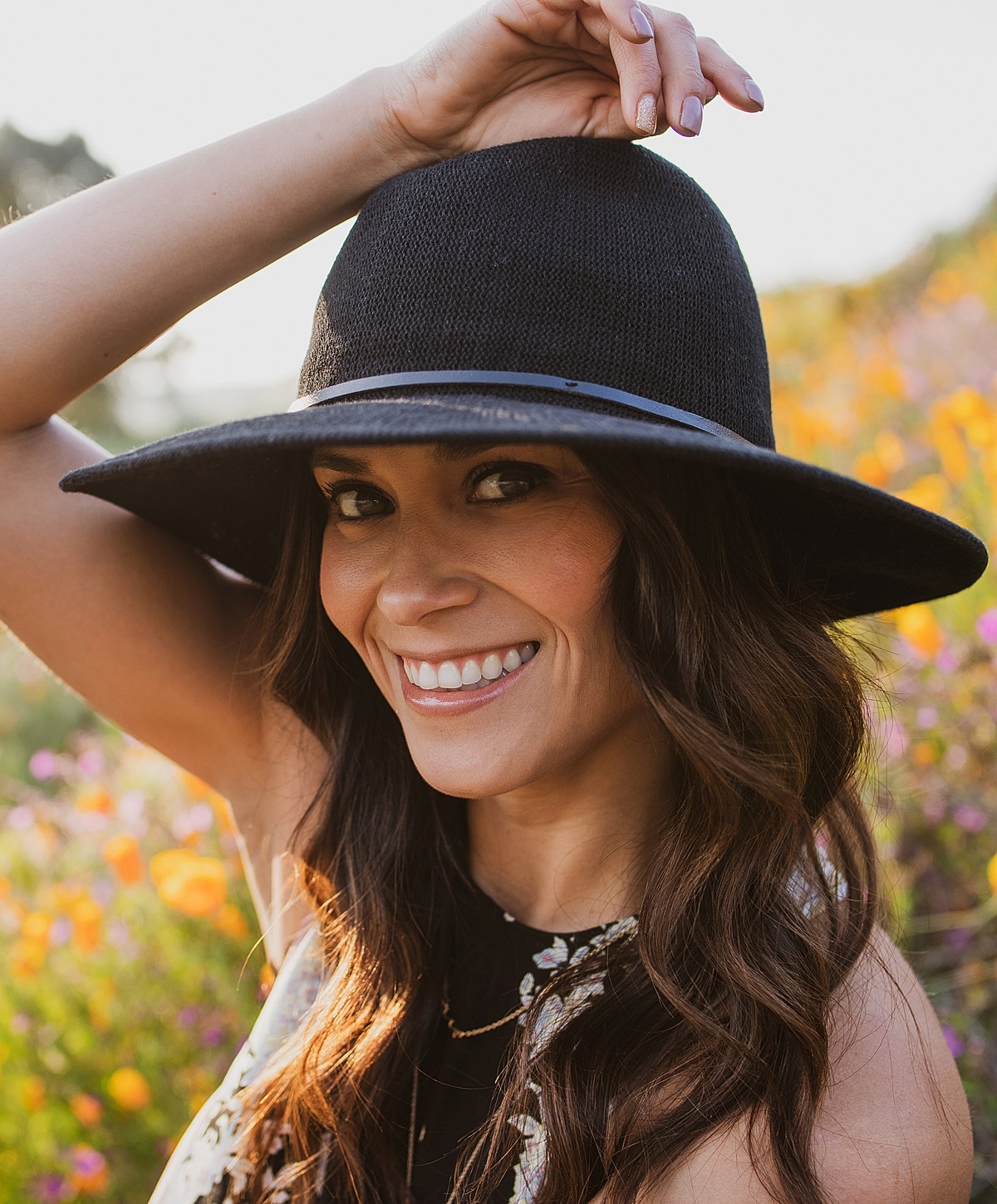 Woman smiling in a black hat with flowers.