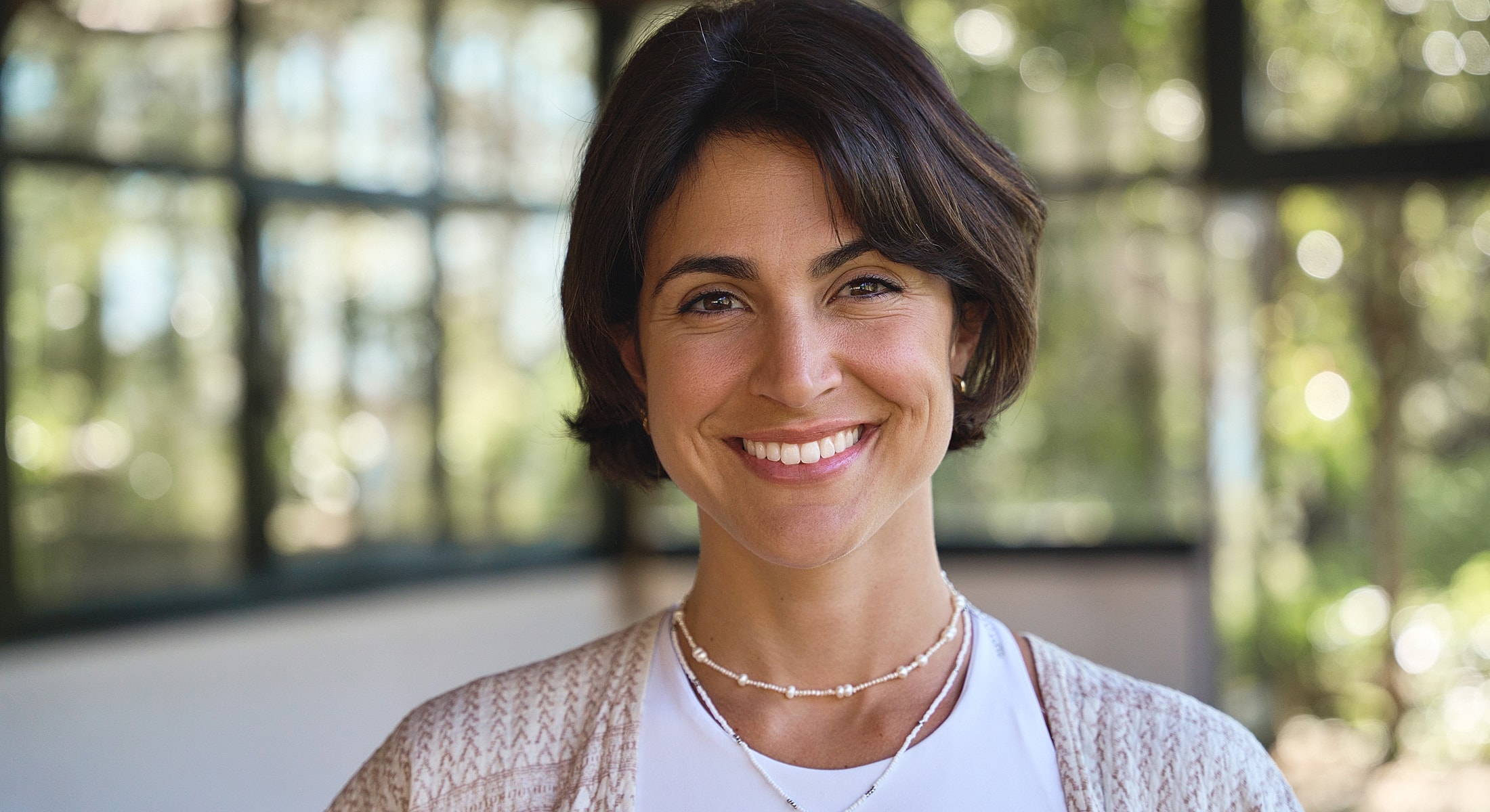 Smiling woman with short hair in bright environment.