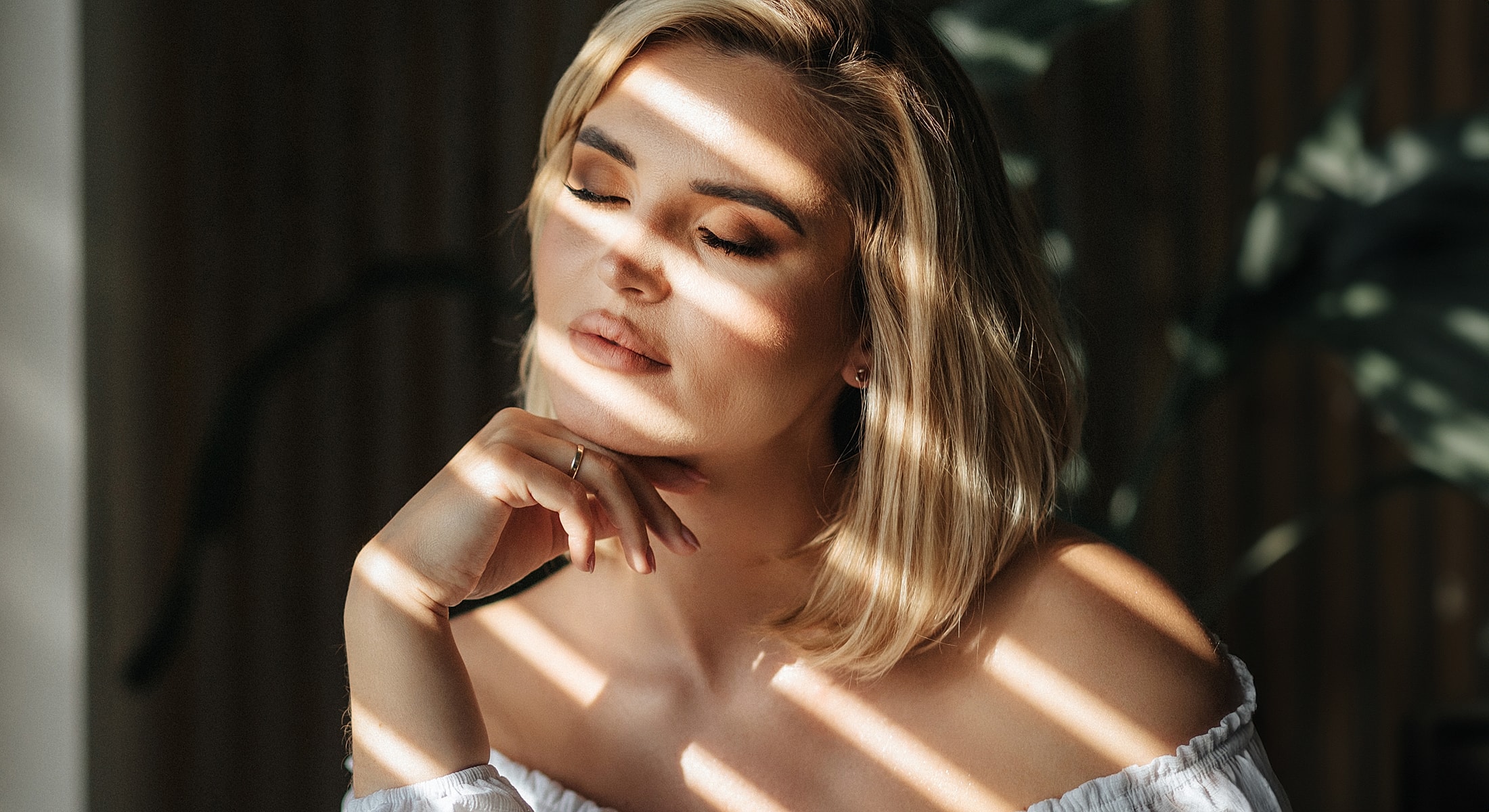 Woman with eyes closed, sunlight casting shadows.