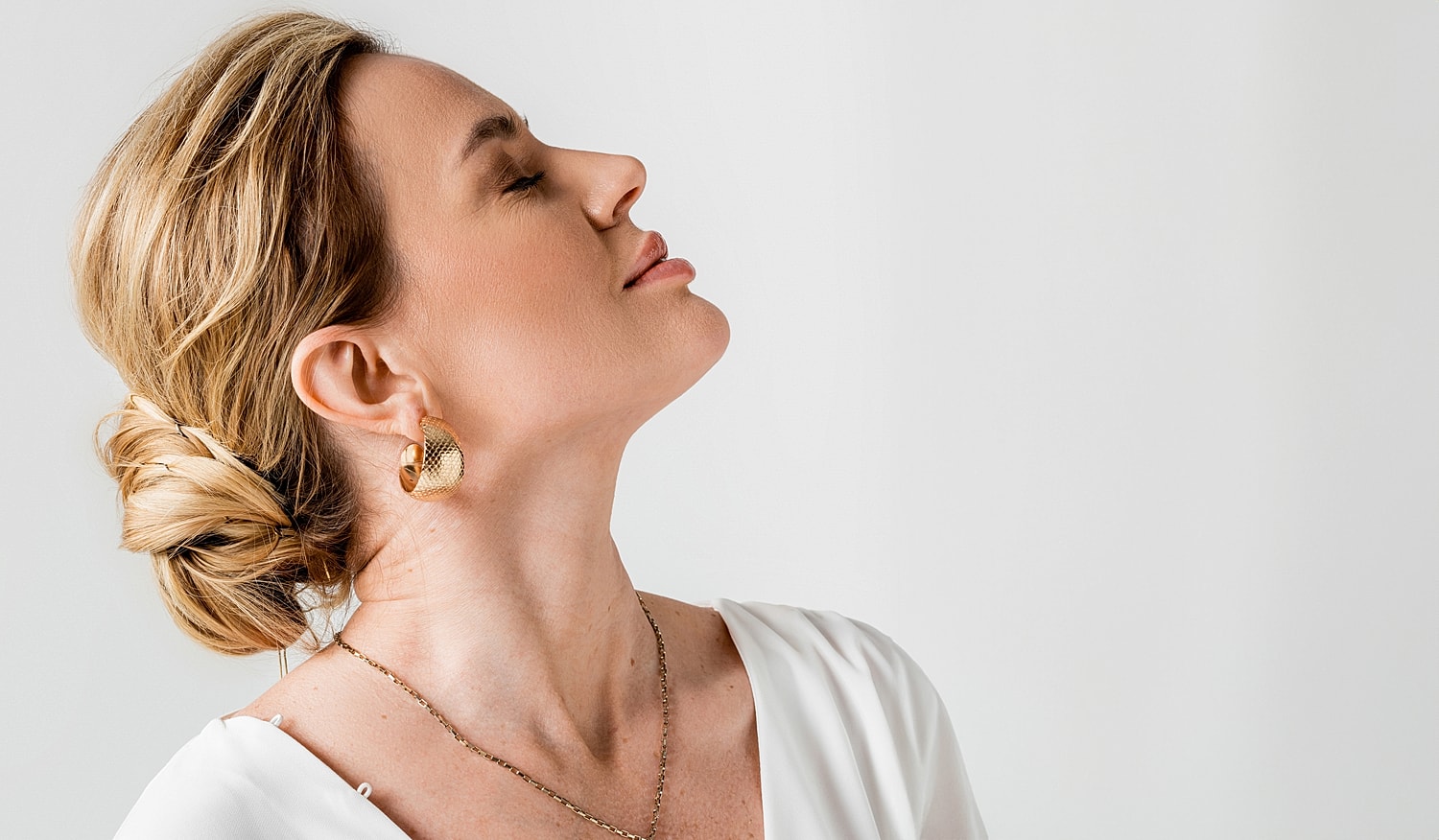 Woman with elegant hairstyle and gold earrings.